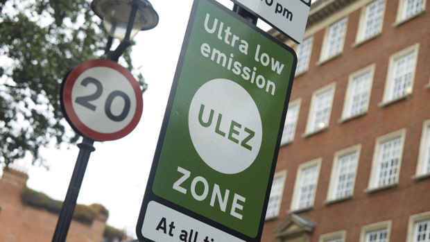 A green Ultra low emissions zone sign on a London road next to a 20mph speed limit sign